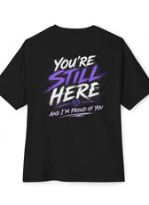 Back view of black oversized mental health awareness gaming shirt featuring "You're Still Here and I'm Proud of You" graphic from the Mouse & Key Still Here Collection